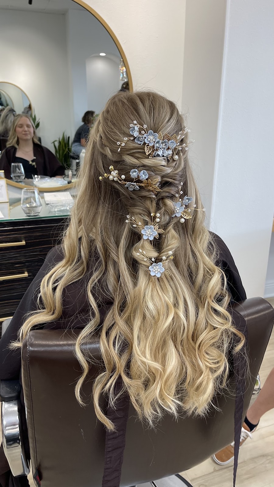 Bridal half-up hairstyle with cascading waves and blue floral hair pins